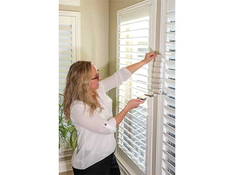 A woman comparing an established window-covering with a sample